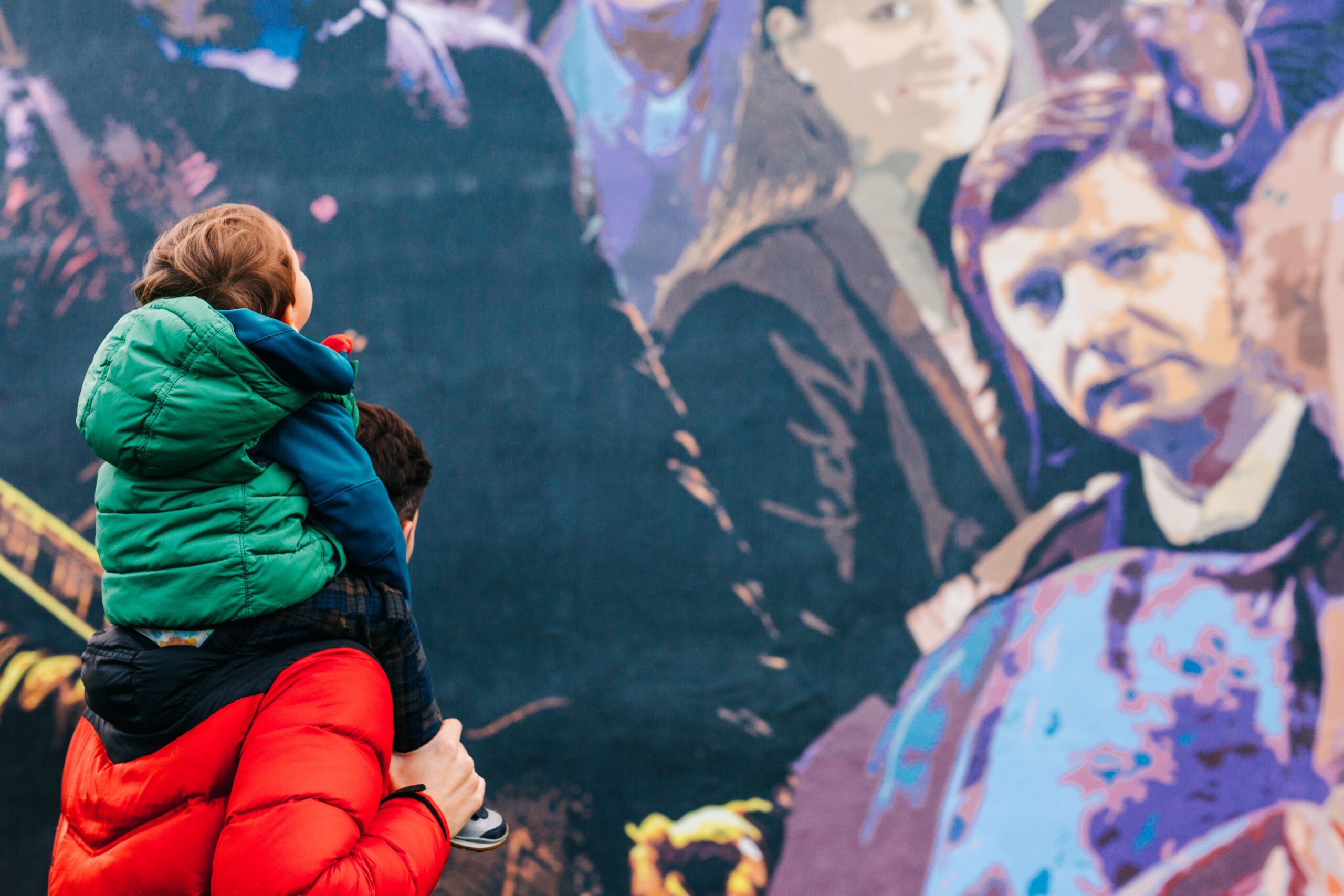 A man and a young boy looking at a wall mural