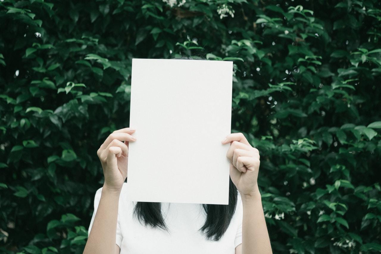 Woman holding blank sheet of paper in front of her face