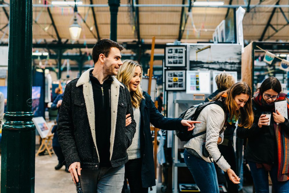 Couple in craft market pointing at goods
