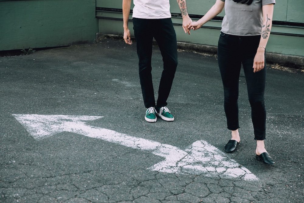 Couple holding hands in front of road markings