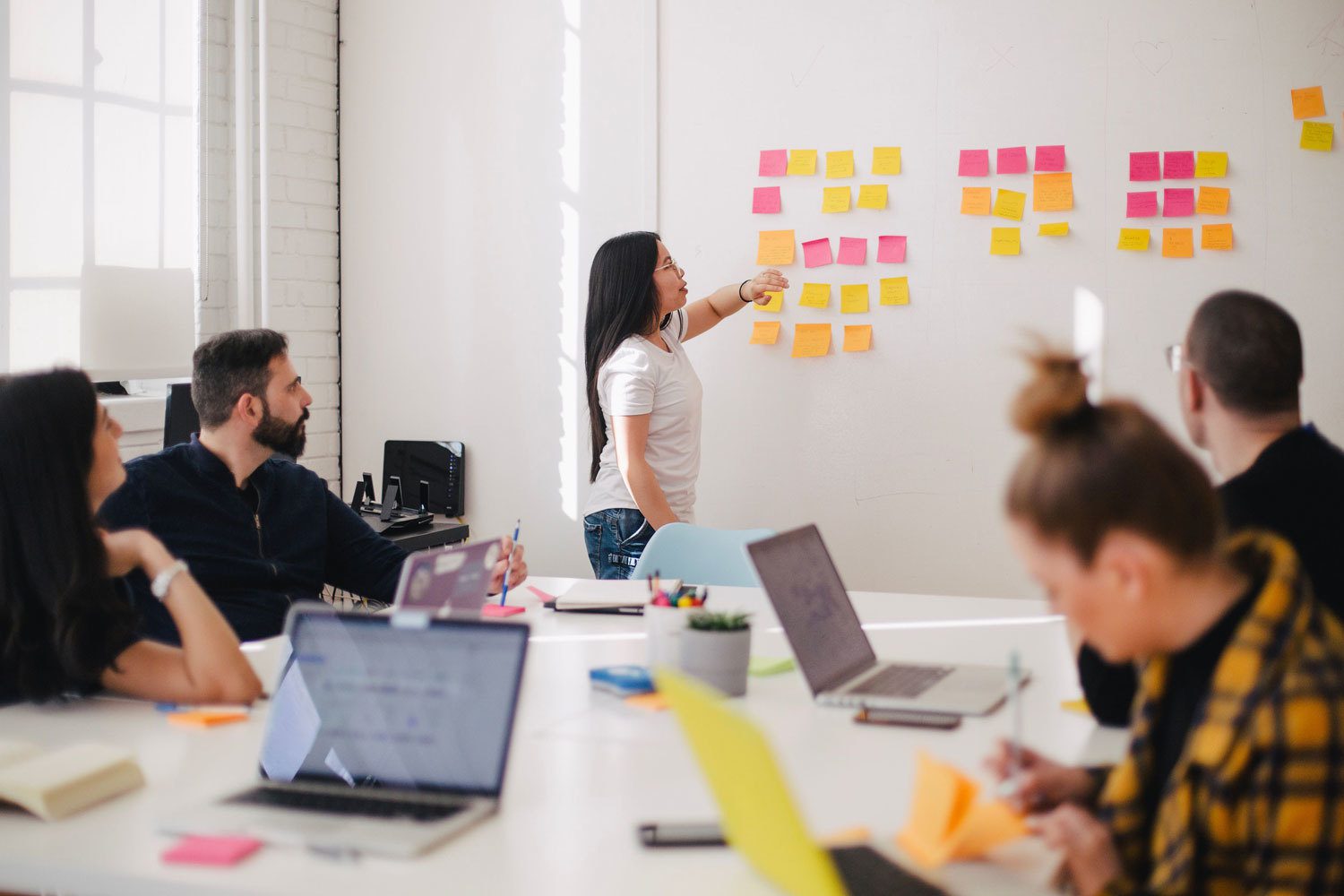 Woman placing sticky notes on a boardroom wall