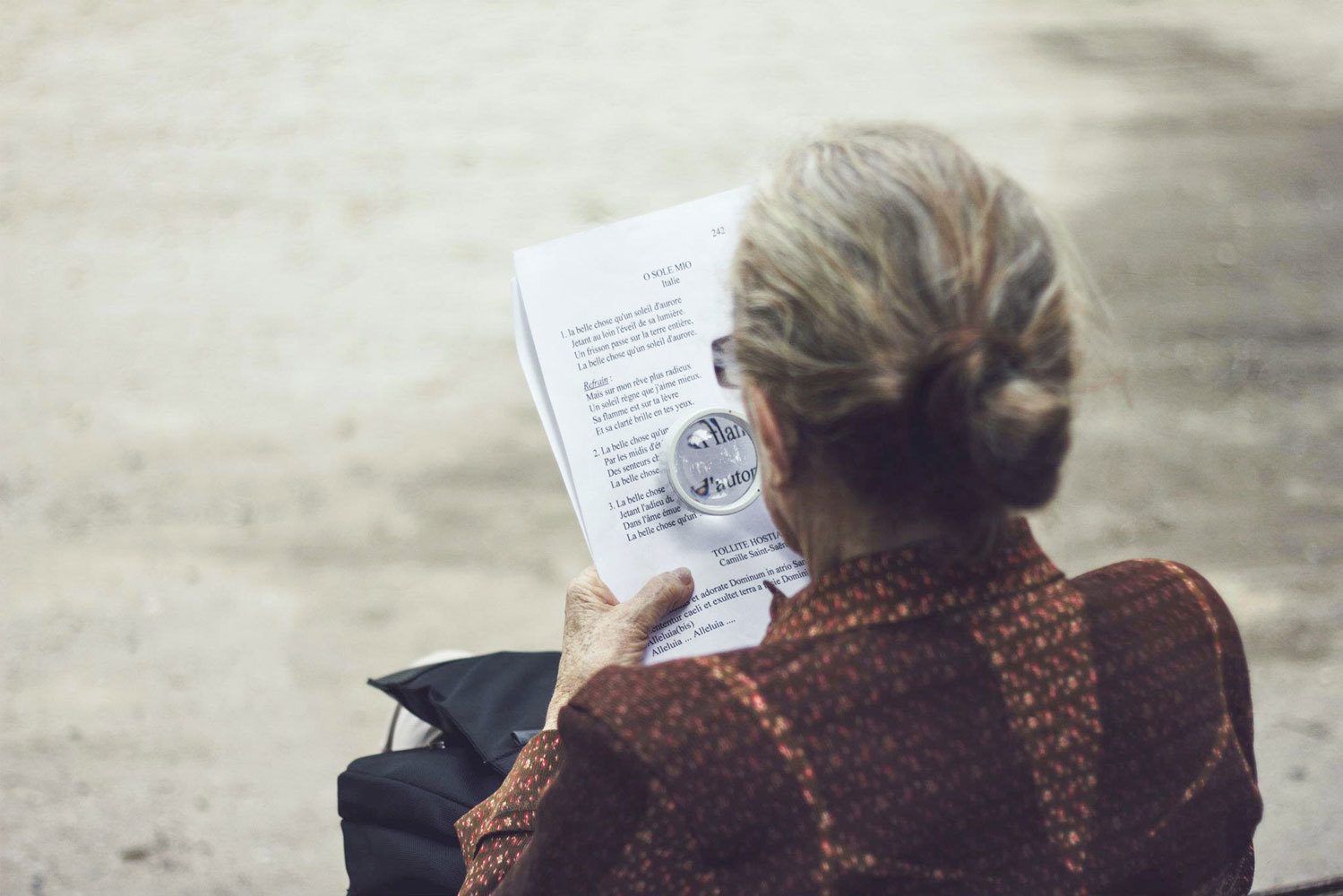 Woman reading a document using a magnifying glass