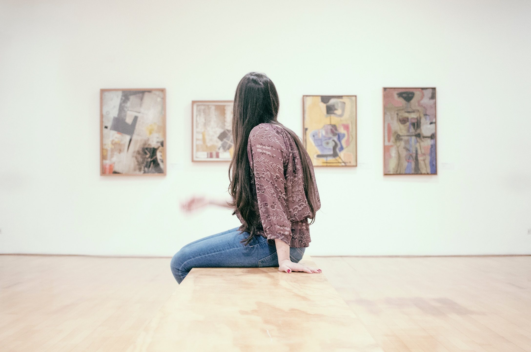 Woman in a gallery looking at abstract paintings