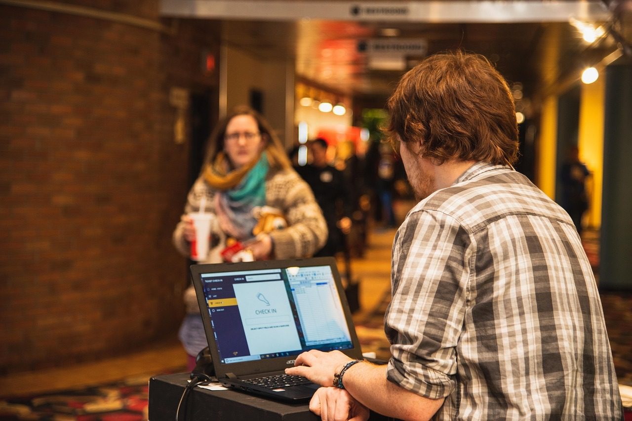 A woman walking toward a man who is working at a venue box office