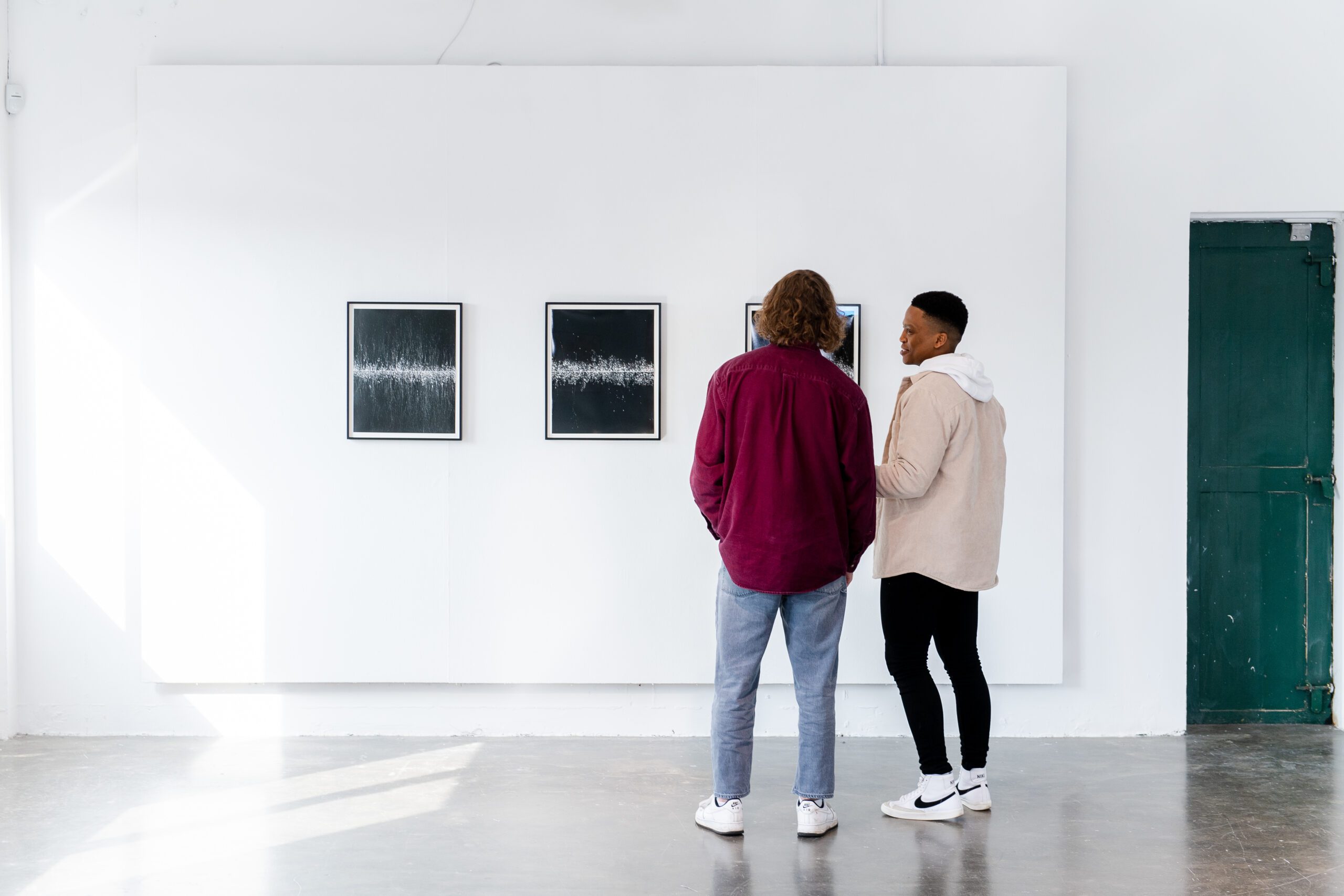 Two men looking at art on a wall