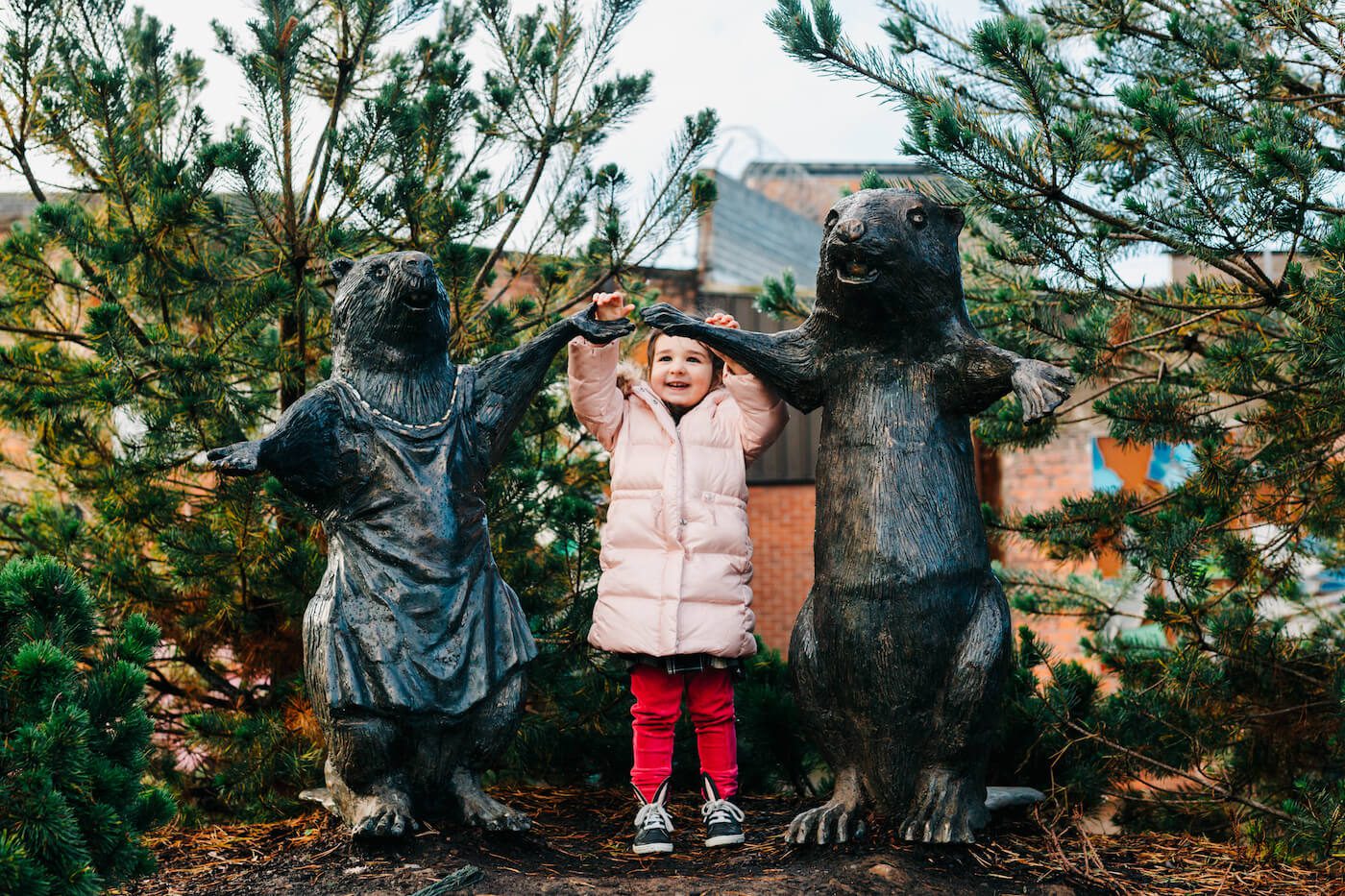 Girl interacting with public art of animal sculptures