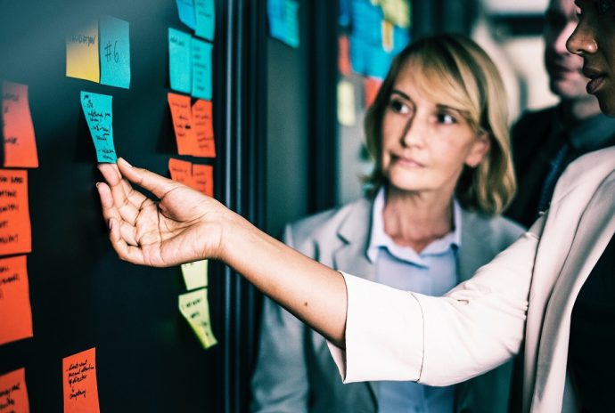 A woman putting a coloured post it on a black wall