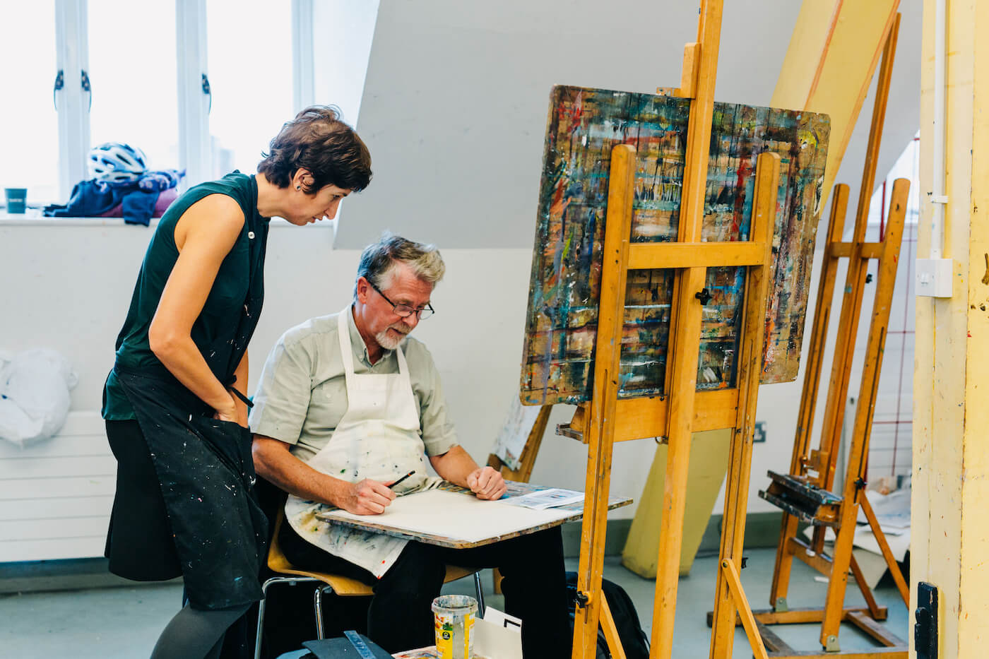 Women in an apron talking to a man painting