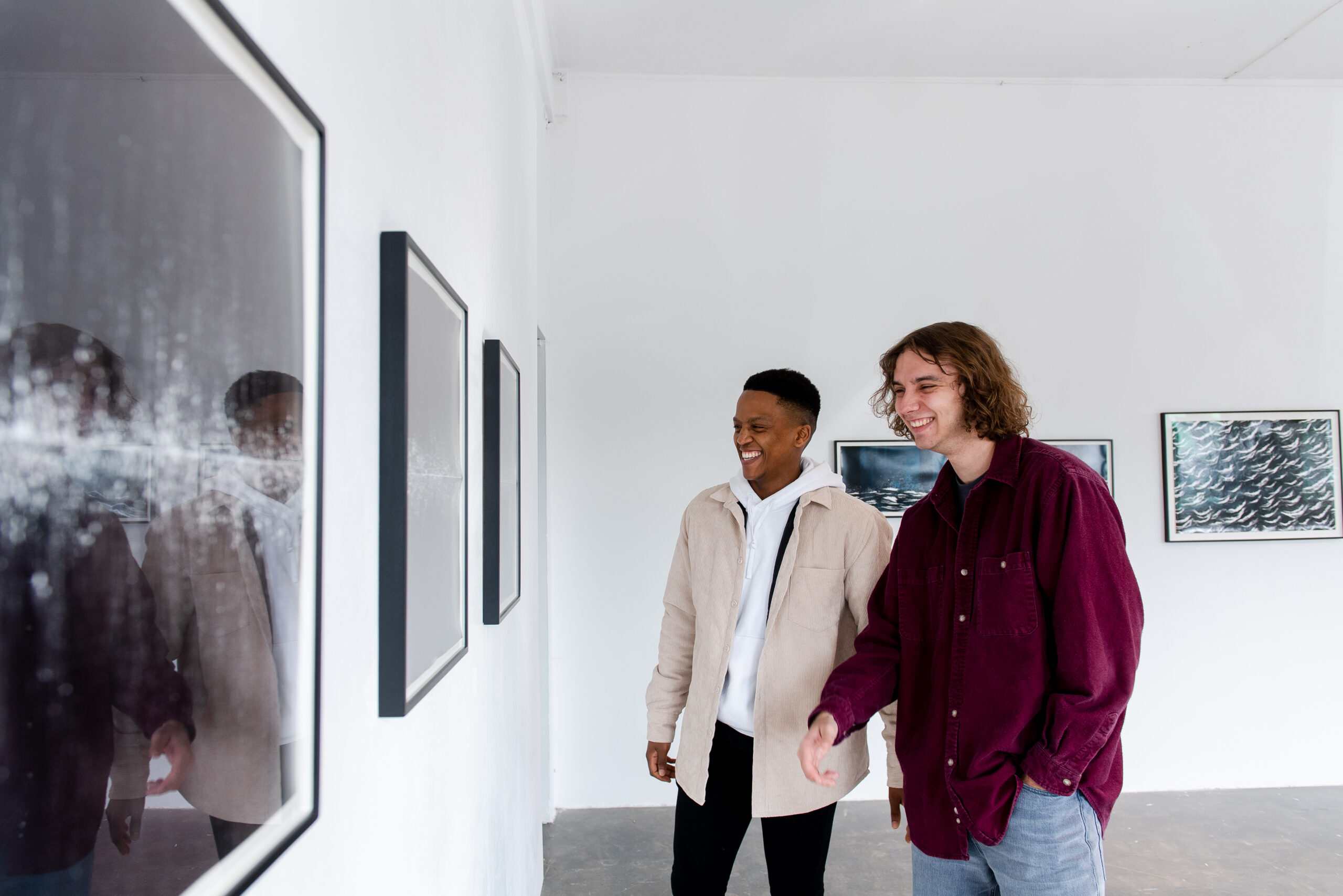 two young men looking at a painting in an art gallery